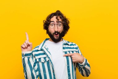 Genç çılgın adam gururlu ve şaşırmış, kendine güvenen, sarı duvara karşı bir numara gibi hisseden.