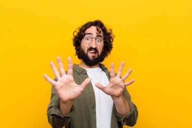 Dehşete kapılmış genç bir adam korku ve panik içinde geri çekilip çığlık atıyor sarı duvara karşı bir kabusa tepki veriyor.