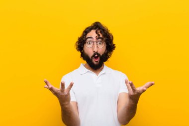 Genç çılgın adam, ağzı açık ve şaşırmış, şaşırmış ve şaşırmış sarı duvara karşı inanılmaz bir sürprizle