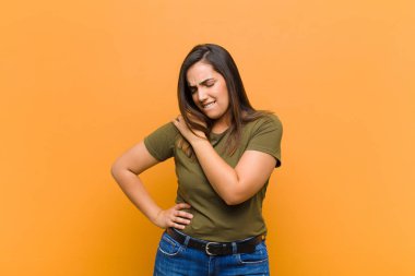 Genç, güzel bir kadın endişeli, hasta, hasta ve mutsuz hissediyor. Ağrılı bir mide ağrısı ya da turuncu duvarda izole edilmiş bir grip geçiriyor.