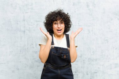 Genç, güzel afro kadın mutlu ve heyecanlı görünüyor. Beklenmedik bir sürprizle şoke oldu. İki eli de açık.