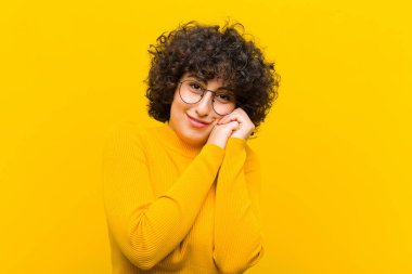 Genç, güzel afro kadın aşık ve sevimli görünüyor. Sevimli ve mutlu. Romantik bir şekilde gülümsüyor.