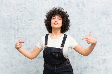 Genç, güzel afro kadın gururlu, kibirli, mutlu, şaşırmış ve tatmin olmuş görünüyor, kendini gösteriyor, kendini kazanan gibi hissediyor.