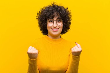 Genç, güzel afro kadın zaferle bağırıyor, gülüyor, mutlu ve heyecanlı hissediyor başarıyı kutlarken.