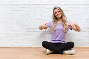 Genç sarışın güzel bir kadın gururlu, kibirli, mutlu, şaşırmış ve tatmin olmuş görünüyor, kendini gösteriyor, kazanan gibi hissediyor.