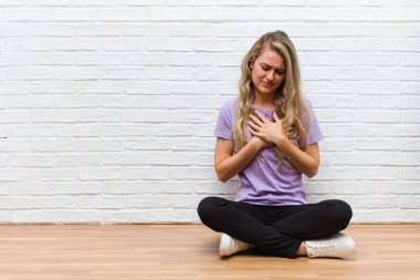 Genç sarışın, güzel bir kadın üzgün, yaralı ve kalbi kırık görünüyor, iki elini de kalbine yakın tutuyor, ağlıyor ve bunalımda.