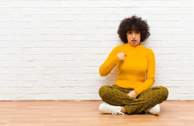 Kafası karışmış, kafası karışmış ve kendine güveni olmayan genç ve güzel bir afro kadın kendini merak edip bana mı soruyor? Yerde oturuyor.