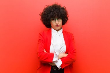 Genç, güzel, afro bir kadın hayal kırıklığına uğramış, hayal kırıklığına uğramış, ciddi görünüyor, kızgın ve kollarını kavuşturmuş.