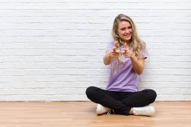 Genç, sarışın, güzel bir kadın kendini mutlu, rahat ve başarılı hissediyor. Kameraya bakıyor ve seni seçiyor.