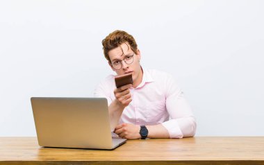 Genç kızıl saçlı işadamı masasında çalışıyor, para konsepti.