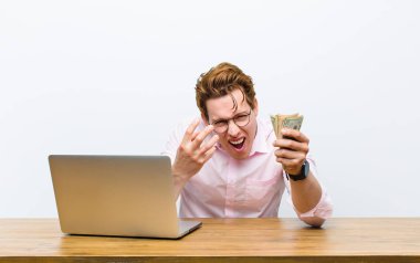 Genç kızıl saçlı işadamı masasında çalışıyor, para konsepti.