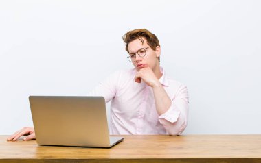 Genç kızıl saçlı işadamı masasında çalışıyor.