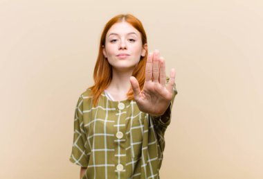 Genç kızıl saçlı güzel kadın ciddi, sert, hoşnutsuz ve kızgın görünüyor.