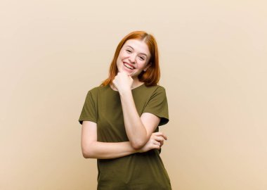 Genç kızıl saçlı güzel kadın gülümsüyor, hayattan zevk alıyor, mutlu, arkadaş canlısı, tatmin olmuş ve tasasız.