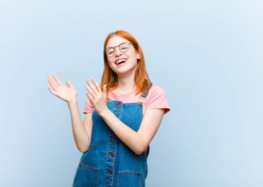 Genç kızıl saçlı güzel kadın mutlu ve başarılı hissediyor, gülümsüyor ve alkışlıyor, alkışlarla tebrik ediyor.