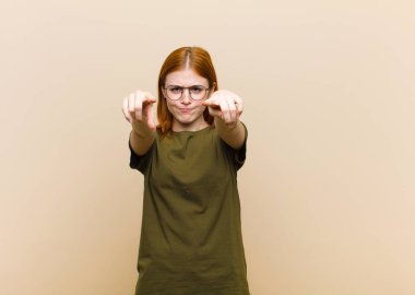 Genç, kızıl saçlı, güzel bir kadın kamerayı iki parmağıyla ve kızgın bir ifadeyle sana görevini yapmanı söylüyor.