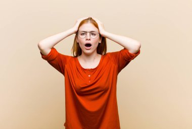 Genç kızıl saçlı, güzel bir kadın dehşete kapılmış ve şok olmuş hissediyor, ellerini havaya kaldırıyor ve bir hata yüzünden panikliyor.