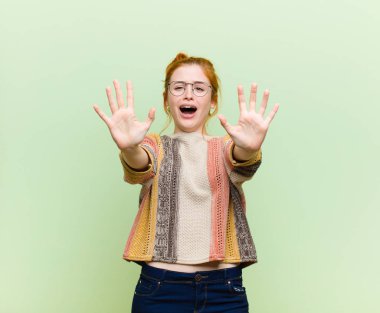 Genç, güzel, kızıl saçlı kadın sersemlemiş ve korkmuş hissediyor. Korkutucu bir şeyden korkuyor. Elleri açık, yeşil duvardan uzak durun diyor.