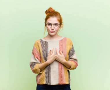 Genç, güzel, kızıl saçlı, kafası karışmış ve tuhaf bakışlarıyla kendini işaret eden kadın, yeşil duvara karşı seçildiği için şaşırmış ve şaşırmıştı.