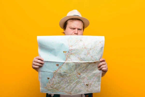 young big size man with a map against flat wall