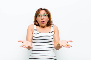 Orta yaşlı, güzel bir kadın şok olmuş, şaşırmış, endişeli ve paniklemiş hissediyor. Stresli ve dehşete kapılmış bir şekilde beyaz duvara bakıyor.