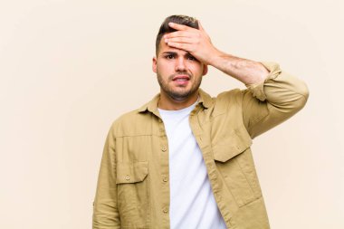 young hispanic man panicking over a forgotten deadline, feeling stressed, having to cover up a mess or mistake against isolated background