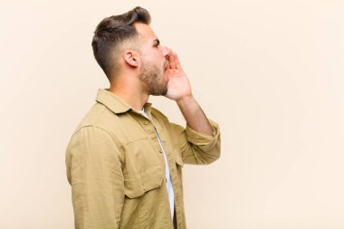 Genç İspanyol profil görüşü, mutlu ve heyecanlı görünüyor, bağırıyor ve izole edilmiş arka plana karşı fotokopi alanı istiyor.