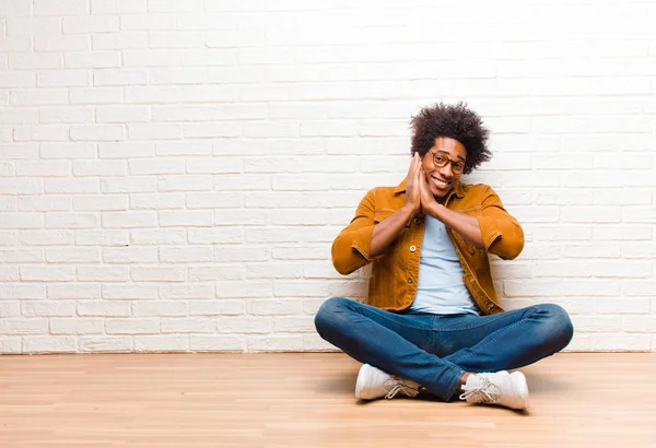 若い黒人男性が愛を感じ かわいい 愛らしい 幸せそうな顔をして 家の床に座っている手でロマンチックな笑顔 — ストック写真