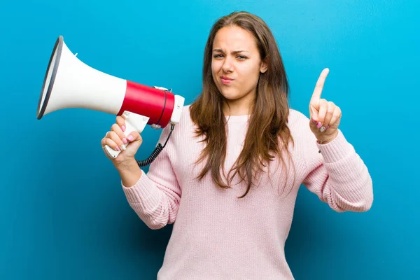 Jonge vrouw met een megafoon tegen blauwe achtergrond — Stockfoto