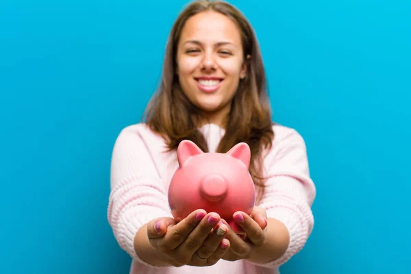 Jonge vrouw met een Piggy Bank tegen blauwe achtergrond — Stockfoto