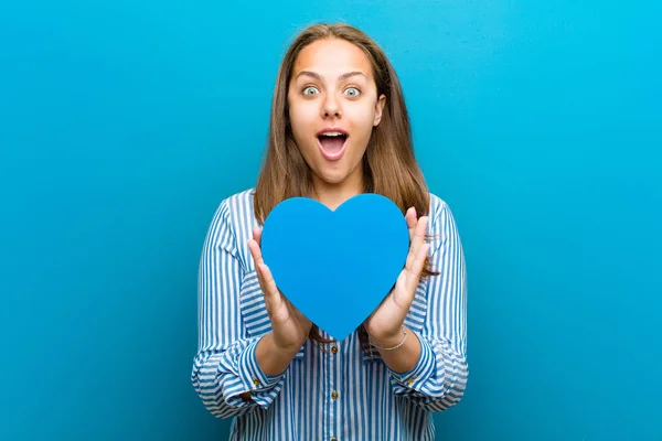 Junge Frau mit Herzform vor blauem Hintergrund — Stockfoto