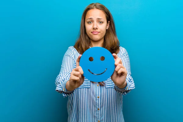 young woman with a smiley face against blue background