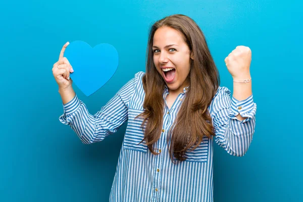 Jonge vrouw met een hart vorm tegen blauwe achtergrond — Stockfoto