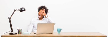 Genç siyah iş adamı mutlu bir şekilde gülümsüyor, şakalaşıyor ve gözetleme deliğinden bakıyor, sırları bir masada gözetliyor.