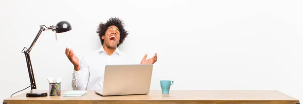 若い黒人実業家は非常に幸せそして驚き成功を祝い机の上で叫び飛び跳ねる — ストック写真