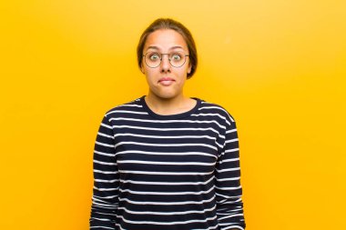 Genç, güzel bir kadın üzgün ve stresli. Kötü bir sürpriz yüzünden üzgün. Turuncu arka planda olumsuz ve endişeli bir bakış var.