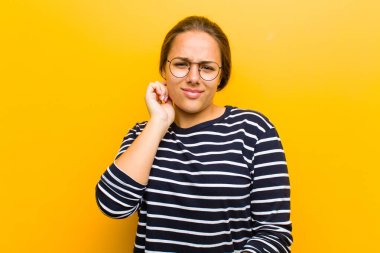 Genç, güzel bir kadın stresli, hayal kırıklığına uğramış ve yorgun hissediyor. Endişeli, sorunlu bir bakışla turuncu arka planda.