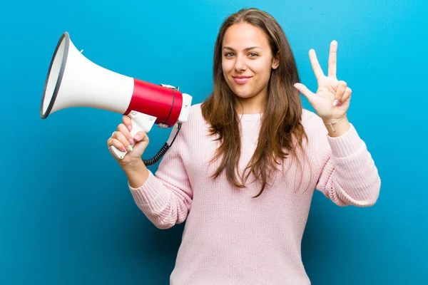 young woman with a megaphone against blue background