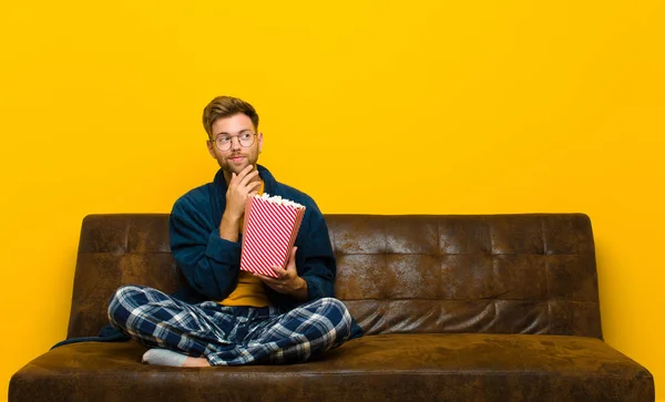 young man sitting on a sofa with popcorns. cinema concept