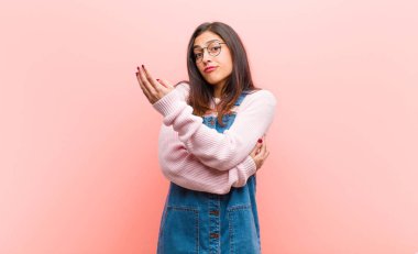 Genç ve güzel bir kadın kendini şaşkın ve cahil hissediyor, şüpheli bir açıklamayı merak ediyor ya da pembe arka plana karşı bir düşünceyi..