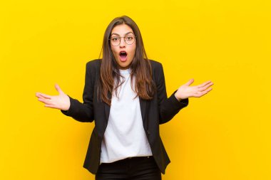 Genç, güzel bir kadın şok olmuş, şaşırmış, endişeli ve paniklemiş hissediyor. Gergin ve korkmuş bir şekilde turuncu duvara bakıyor.