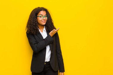 Siyah iş kadını kafası karışık ve cahil hissediyor, şüpheli bir açıklama ya da turuncu duvara karşı düşüncelerini merak ediyor.