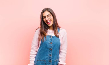 Büyük, dostane, kaygısız bir gülümsemesi olan genç ve güzel bir kadın. Olumlu, rahat ve mutlu görünüyor. Pembe arka planda takılıyor..