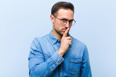 Genç yakışıklı adam sessizlik ve sessizlik istiyor, parmağıyla ağzının önünde işaret ediyor, 