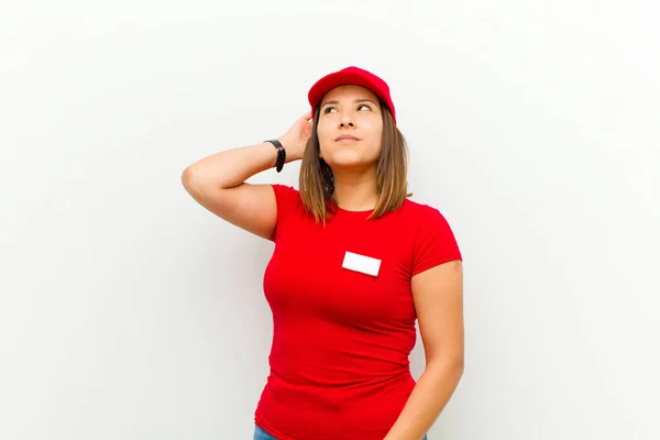 delivery woman smiling cheerfully and casually, taking hand to head with a positive, happy and confident look against white background