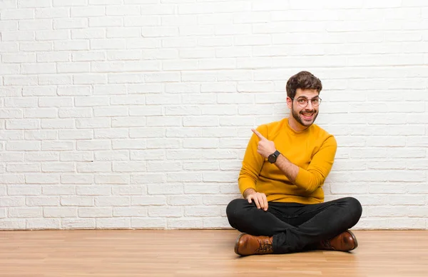 Joven Hombre Guapo Sentado Suelo Casa Contra Textura Pared Ladrillo — Foto de Stock