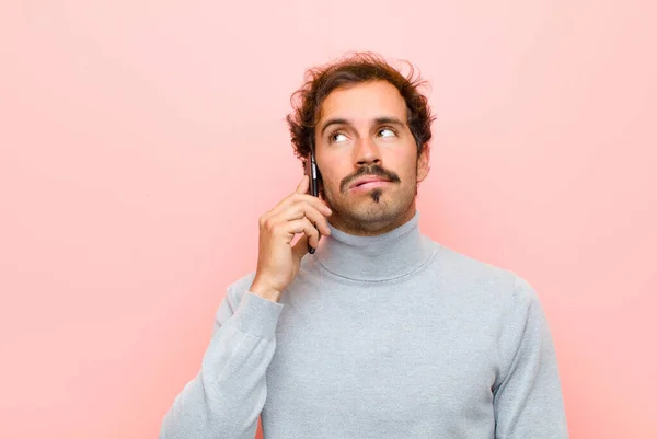 Jonge Knappe Man Met Een Smartphone Tegen Roze Platte Muur — Stockfoto