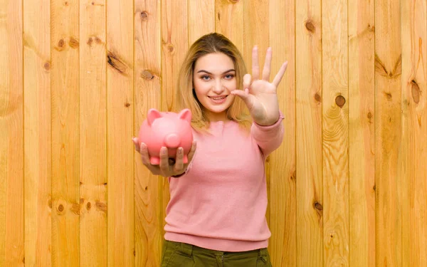 Jovem Mulher Loira Bonita Com Banco Porquinho Contra Parede Madeira — Fotografia de Stock