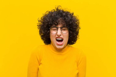 Genç, güzel afro kadın agresif bir şekilde bağırıyor, çok kızgın, hayal kırıklığına uğramış, öfkeli ya da rahatsız olmuş görünüyor.