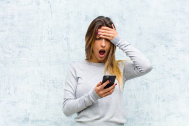 Akıllı telefonlu güzel bir kadın grunge duvarına karşı.